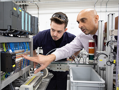 Male mentor speaking to Food and Drink Engineering Maintenance Technician apprentice about Automation fault finding