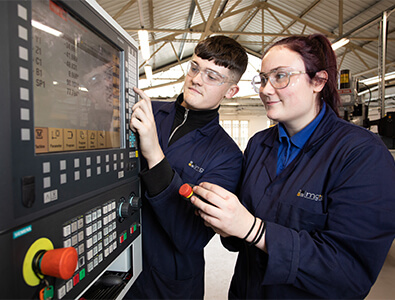 Two engineering apprentices using CNC machine