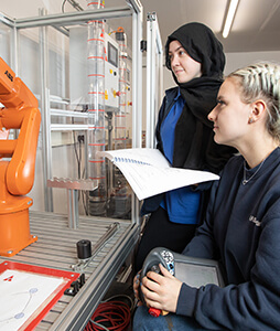 Two female Mechatronics maintenance technician apprentices learning robotics programming