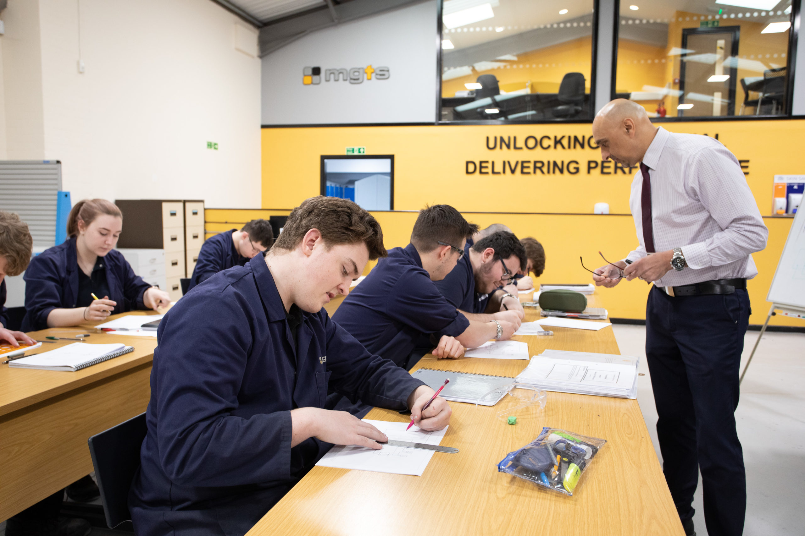 Engineering apprentices technical drawing with teacher in classroom