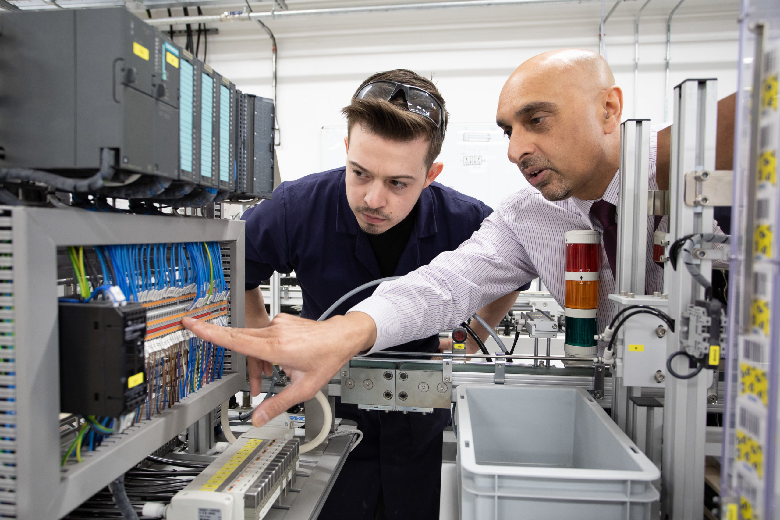 Male mentor speaking to Food and Drink Engineering Maintenance Technician apprentice about Automation fault finding