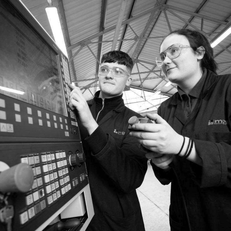 Two engineering apprentices using CNC machine