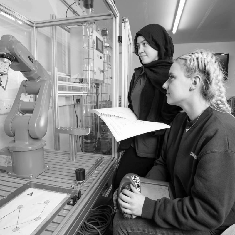 Two female Mechatronics maintenance technician apprentices learning robotics programming