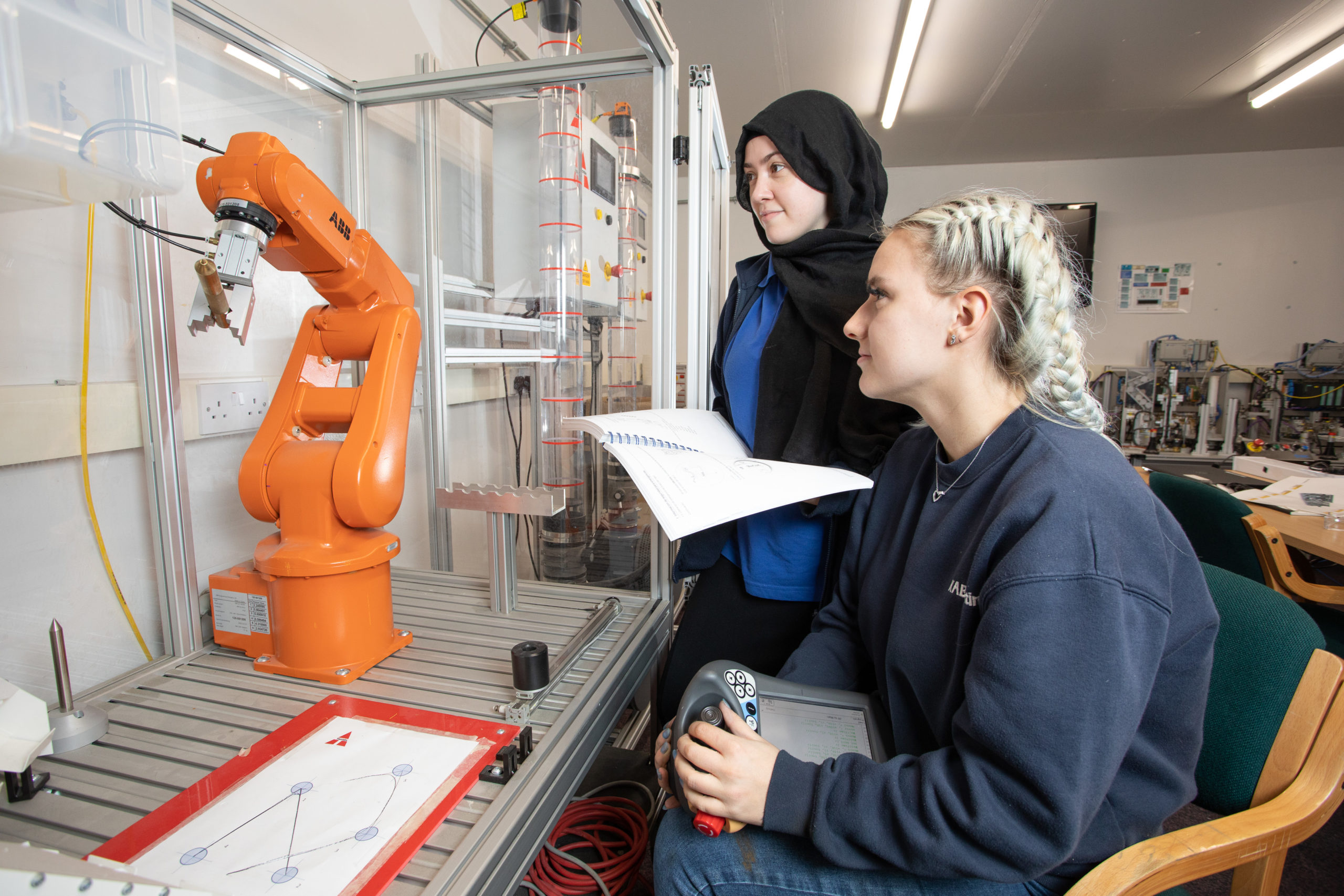 Two female Mechatronics maintenance technician apprentices learning robotics programming